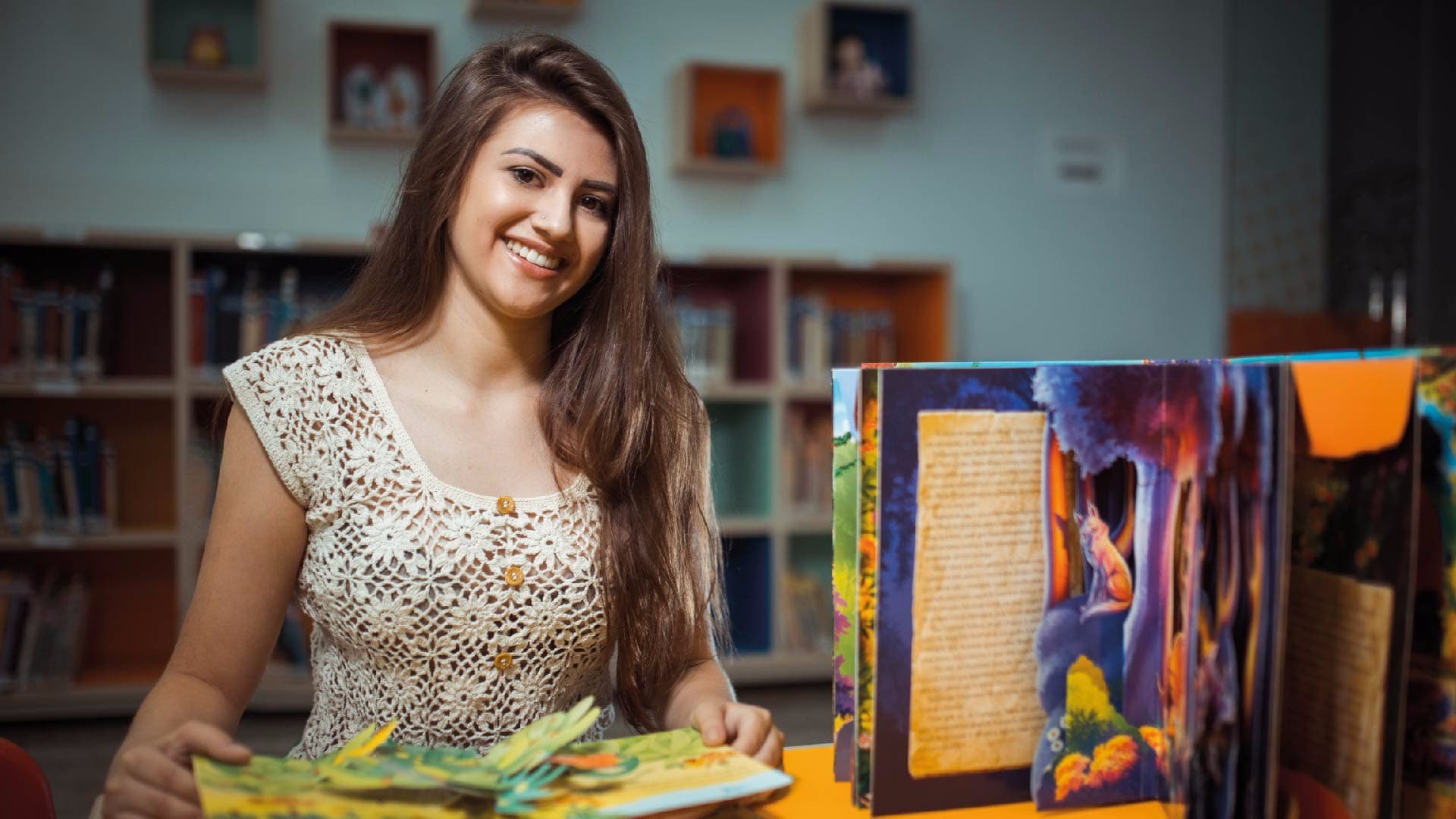 Aluna sorrindo enquanto lê um livro